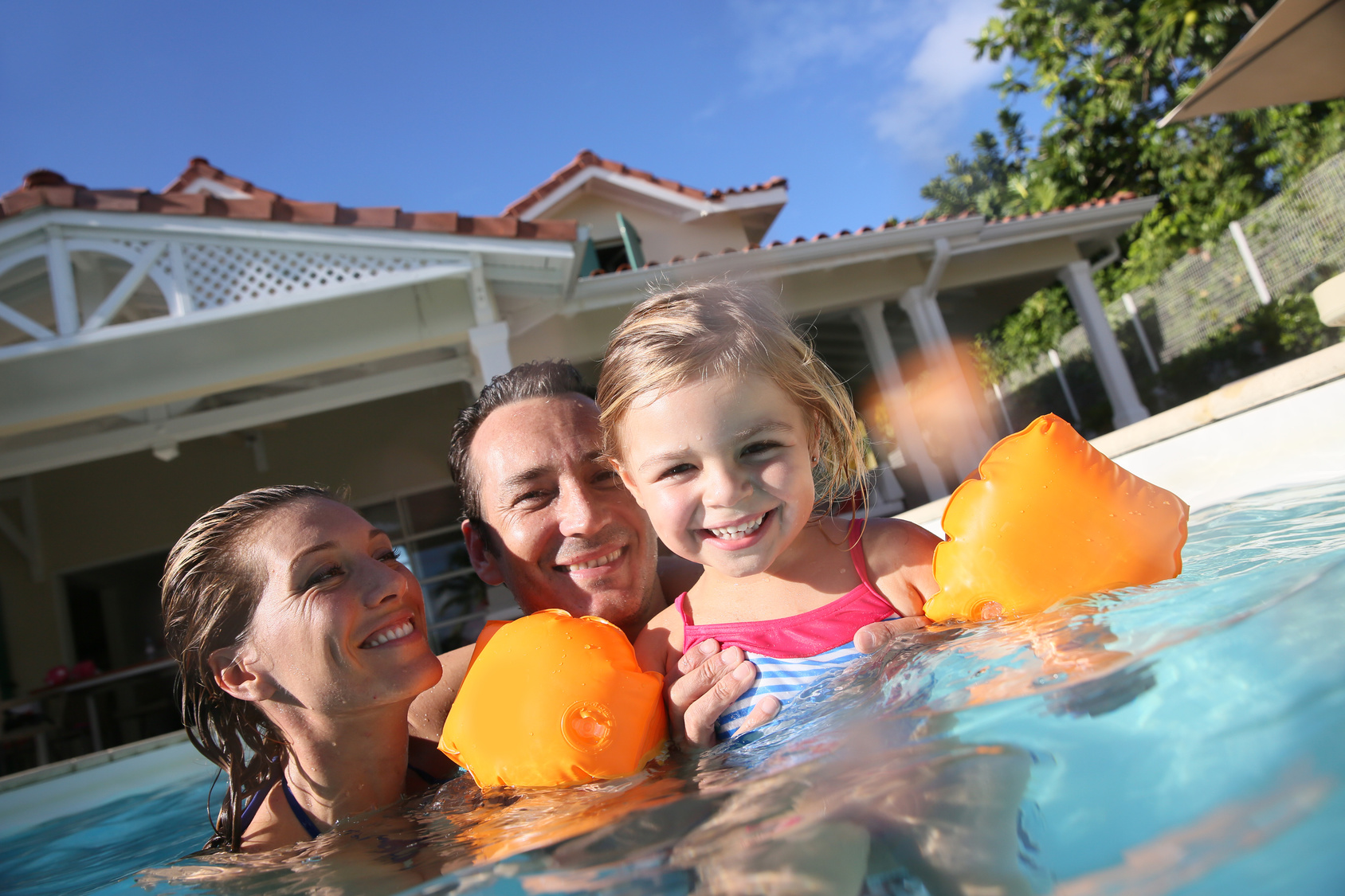 Family playing in swimming pool of private villa